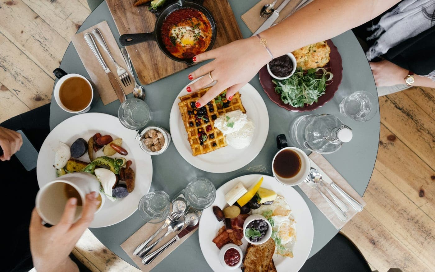 A table of shared plates with someone reaching in