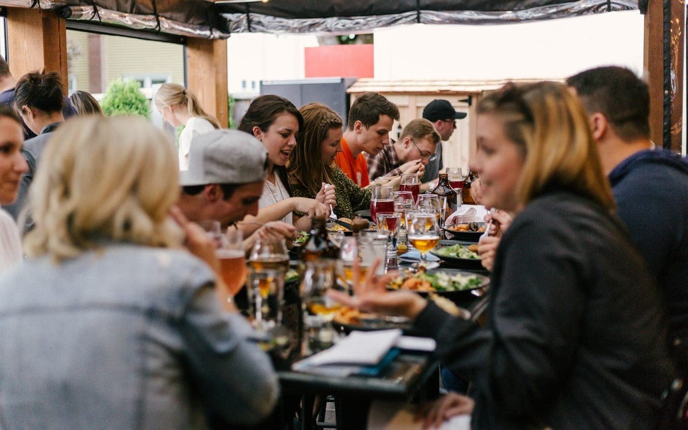 A long table of friends eating and drinking together
