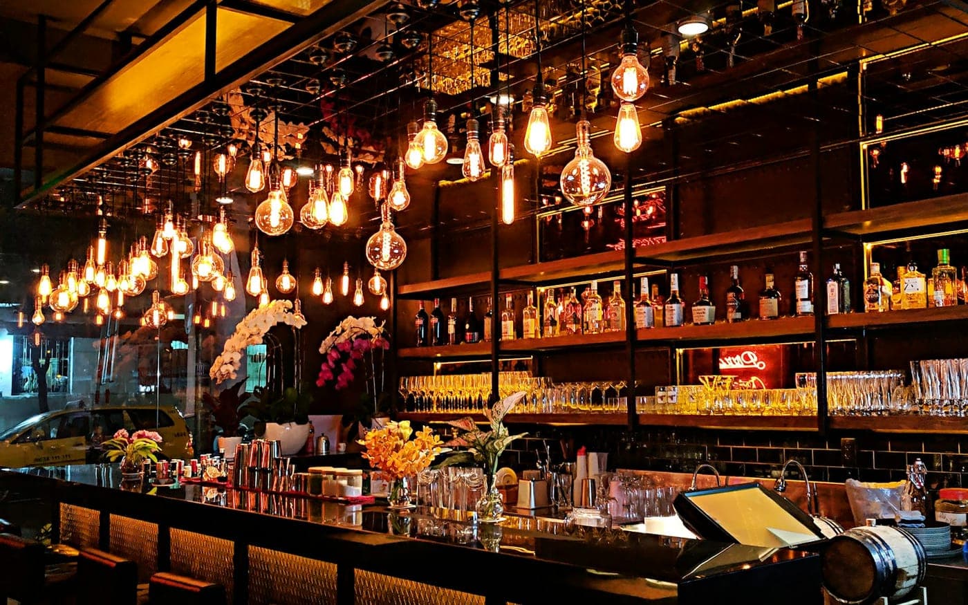 A warmly lit bar with hanging filament lights